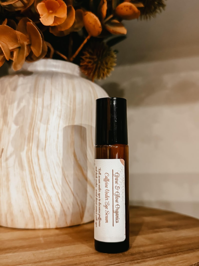 K&ouml;nnte beinhalten: Eine braune Glasrollflasche mit schwarzem Verschluss und einem wei&szlig;en Etikett mit der Aufschrift "Grow & Glow Organics Caffeine Under Eye Serum Roll serum under eyes to decrease puffiness and dark circles. A good boost for almost any skin."