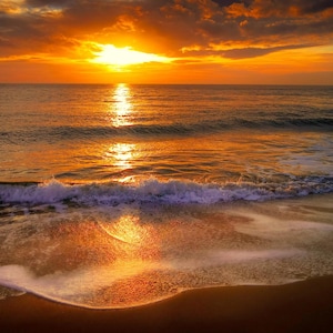 Pode incluir: Um pôr do sol vibrante sobre o oceano com um sol brilhante laranja e amarelo acima do horizonte. A luz dourada reflete-se na água azul escura e nas ondas suaves que banham a praia de areia molhada em primeiro plano.