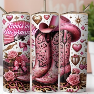 Puede incluir: Un vaso blanco con un diseño de botas y sombrero de vaquero rosas. El vaso presenta el texto "Boots on the ground!" junto con corazones, rosas y una base con estampado de leopardo. Se incluye una pajita dorada.