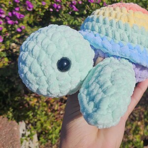 May include: A crocheted sea turtle toy with a rainbow shell. The turtle is made of soft, light blue yarn and has a black eye.