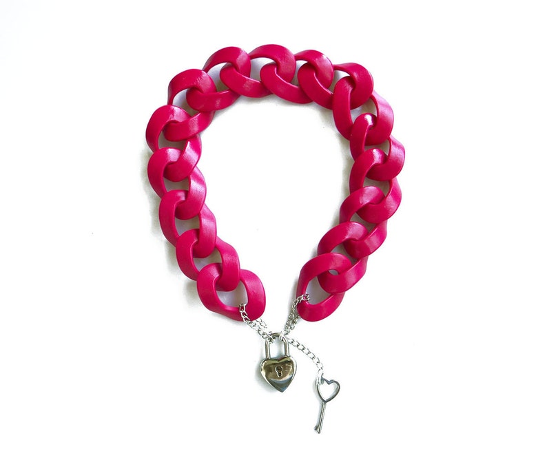 May include: A bright pink plastic chain necklace with a silver heart-shaped padlock and key.