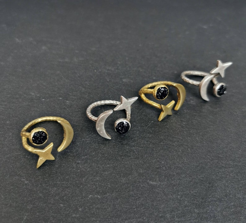 May include: Four gold and silver rings with black gemstone accents. Each ring features a crescent moon and a star design.