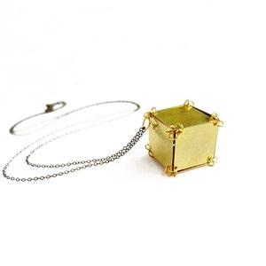 May include: A gold necklace with a geometric cube pendant. The cube is made of brass and has a hammered finish.
