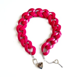 May include: A bright pink plastic chain bracelet with a heart-shaped padlock and key.