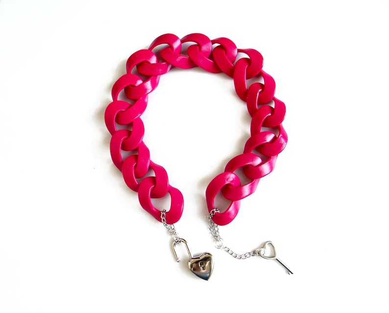 May include: A bright pink plastic chain bracelet with a heart-shaped padlock and key.