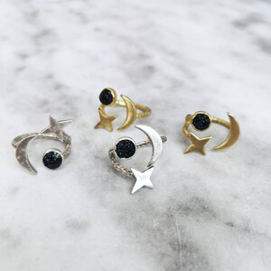 May include: Three adjustable rings featuring a crescent moon and star design. Each ring has a black stone in the centre of the moon.
