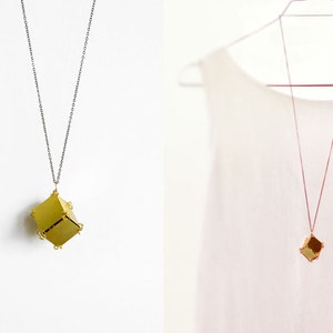 May include: Two gold necklaces with geometric pendant charms. The necklace on the left has a silver chain and the necklace on the right has a gold chain.