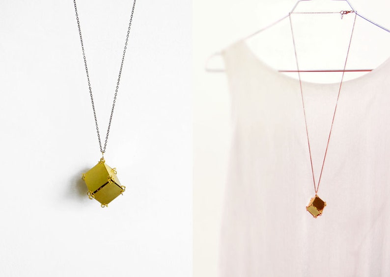 May include: Two gold necklaces with geometric pendant charms. The necklace on the left has a silver chain and the necklace on the right has a gold chain.