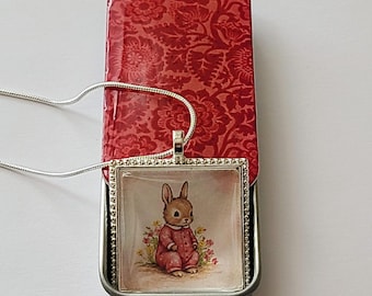 Pendant Necklace with Whimsical Baby Bunny in Pink Pajamas & Hand-Decorated, Colorful Red Floral Decorative Tin with a Glossy Resin Finish.