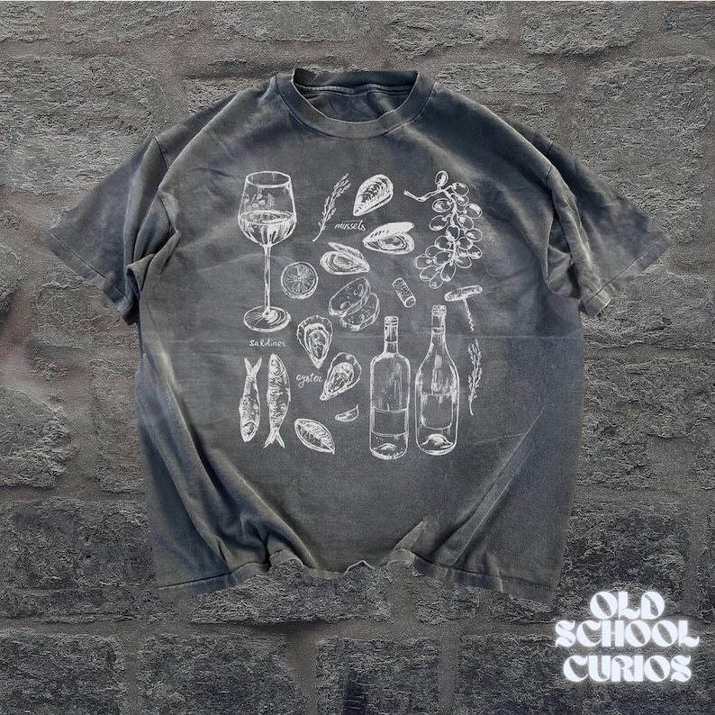 May include: Gray t-shirt with a white illustration of wine, oysters, mussels, sardines, and wine bottles. The text "Old School Curios" is at the bottom right corner of the shirt.