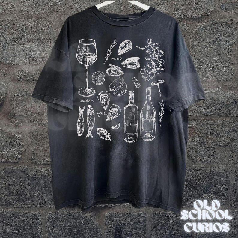 May include: Black t-shirt with a white illustration of wine, oysters, mussels, sardines, and grapes. The shirt also features two wine bottles, a corkscrew, and the text "Old School Curios" at the bottom.