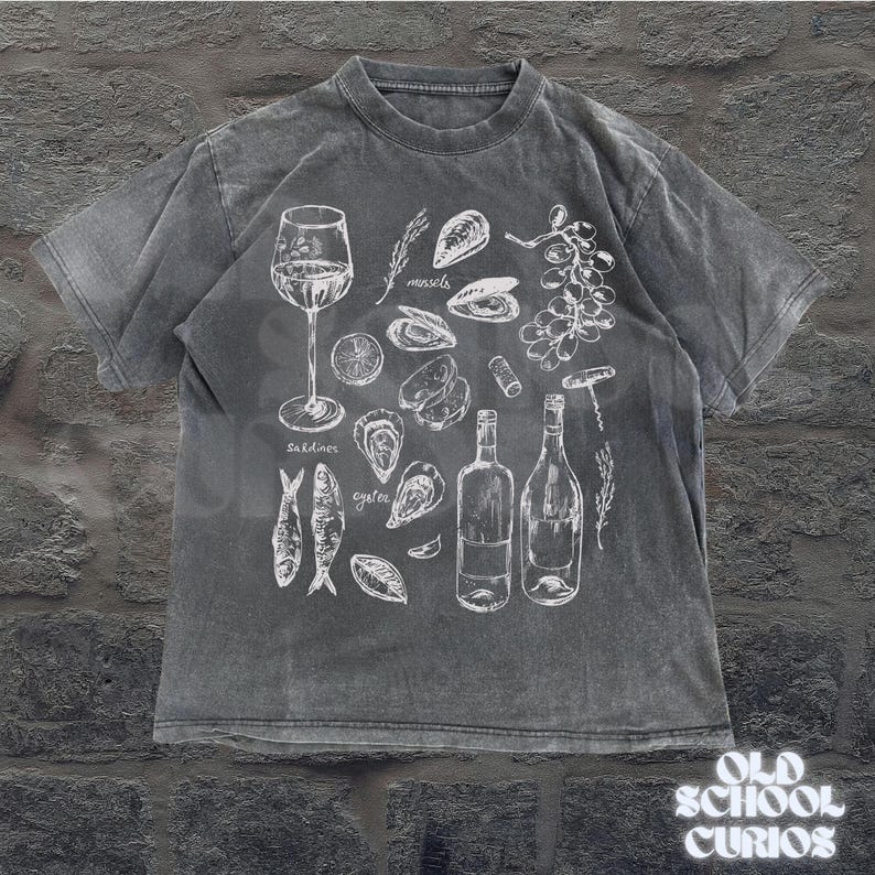 May include: A gray t-shirt featuring a white illustration of seafood and wine. The design includes a wine glass, bottles, oysters, mussels, sardines, and grapes. The text "Old School Curios" is at the bottom right.