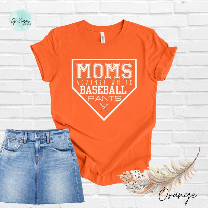 May include: Orange t-shirt with a white baseball diamond graphic that says "MOMS AGAINST WHITE BASEBALL PANTS".