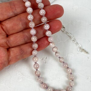 May include: A delicate necklace made with light pink and white beads. The necklace is strung on a thin silver chain with a lobster clasp.