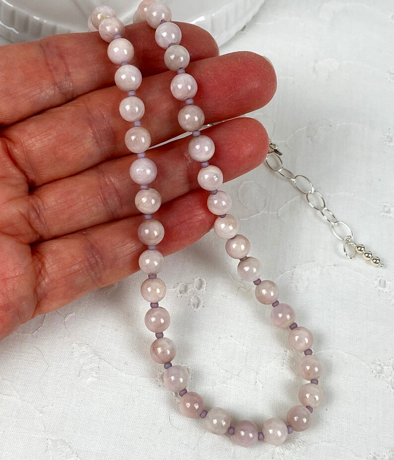 May include: A delicate necklace made with light pink and white beads. The necklace is strung on a thin silver chain with a lobster clasp.