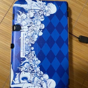 May include: Blue Nintendo 3DS XL case with a white design featuring a group of characters from a video game. The case has a diamond pattern background.