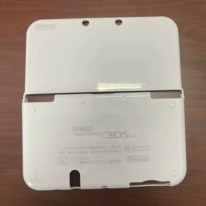 May include: A white Nintendo 3DS LL handheld games console, open to show the screen and controls. The console has a glossy finish and the Nintendo logo is visible. The text "new Nintendo 3DS LL" is printed on the bottom half of the console.