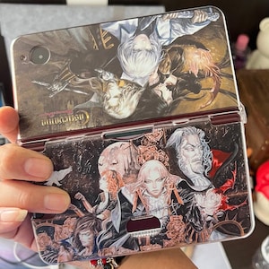 Könnte beinhalten: Ein tragbares Spielgerät mit Kunstwerken aus der Castlevania-Serie. Das Gerät ist geöffnet und zeigt eine detaillierte Illustration von Charakteren und Szenen in dunklen Tönen. Der obere Bildschirm zeigt ein komplexes Bild, während der untere Bildschirm zusätzliche Charaktere zeigt.