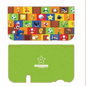May include: Green and red Nintendo 3DS XL skin featuring a Super Mario Bros. design with characters like Mario, Luigi, and Yoshi. The skin has a green background with a yellow star and the text "Super Mario Bros. 3DS™ Nintendo".