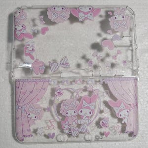May include: Transparent phone case decorated with pink cartoon characters, bows, hearts, and musical notes. The design incorporates a stage curtain theme and various character illustrations in a cute style. The case is designed for a phone.