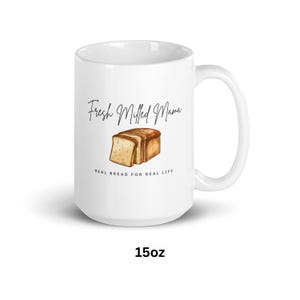 Può includere: Una tazza in ceramica bianca con una grafica in bianco e nero di fette di pane e il testo "Fresh Milled Mama Real Bread for Real Life". La tazza è da 15 once.