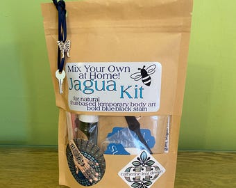 May include: A brown paper pouch containing a Jagua kit for temporary body art. The label reads Mix Your Own at Home! Jagua Kit for natural fruit-based temporary body art bold blue-black stain. A dark blue ribbon with a butterfly and key charm is attached.