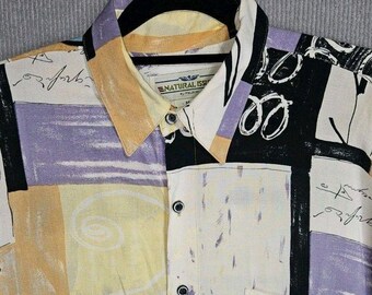 Puede incluir: Una camisa de botones con un estampado abstracto multicolor con bloques de color amarillo, lavanda, negro y blanco. El diseño incluye escritura a mano, arte lineal circular y un bolsillo en el pecho. Una etiqueta dice NATURAL ISSUE.
