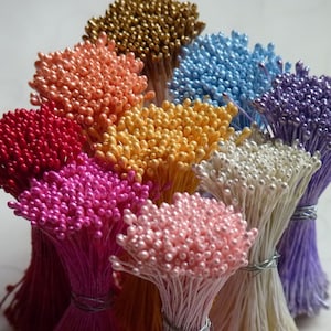 May include: Assortment of colorful flower stamens, also known as flower picks, in various colors including gold, peach, red, yellow, pink, white, and purple. These are used for crafting and floral arrangements.