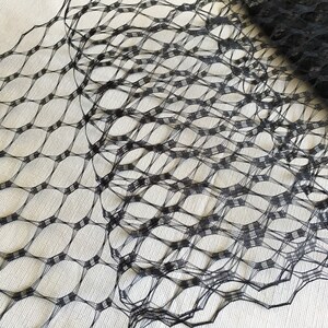 May include: Black mesh fabric with a diamond pattern. The fabric is soft and delicate, and it has a slightly stretchy feel.