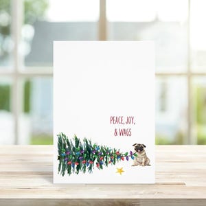 May include: A Christmas card featuring a pug pulling down a decorated Christmas tree with the text "Peace, Joy, & Wags".