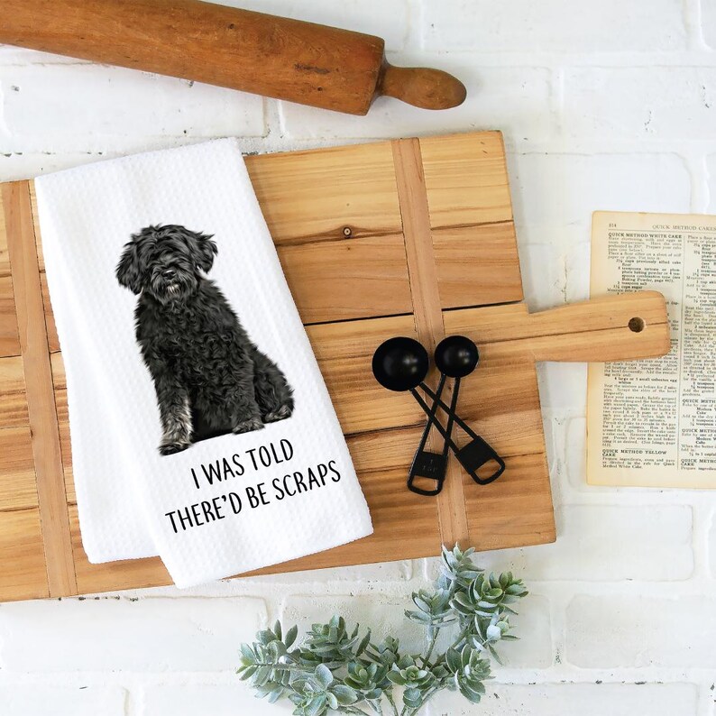 May include: White kitchen towel with a black and white illustration of a Portuguese Water Dog. The text "I was told there'd be scraps" is printed on the towel.