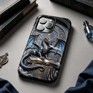 May include: A smartphone case featuring a detailed embossed design of a blue and gold dragon perched on an open book. The background displays a circular stained glass window pattern with intricate metallic gold accents and wisps of white smoke.