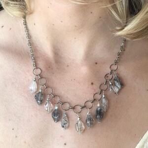 Necklace of crystal quartz gemstone, which offer strength.  Stones hang from metal circles, stung on a chain with glass embedded stones.