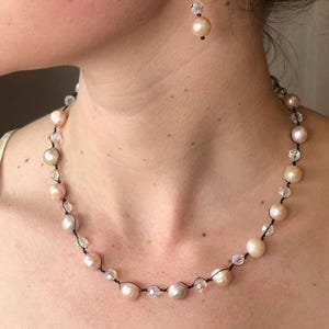 May include: A delicate necklace with a black cord and alternating ivory and crystal beads. The necklace is worn by a person with a light complexion.