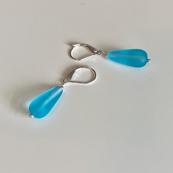 Soft sea glass type frosted aqua blue teardrop earrings. Fashioned with a quality sterling silver lever back clasp.