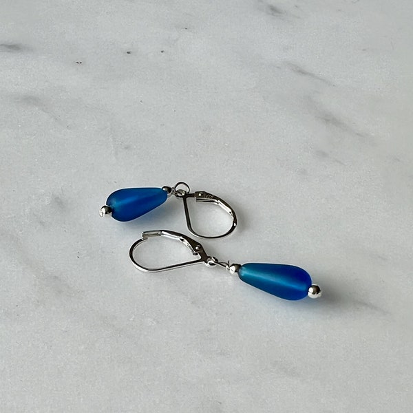 Soft sea glass type frosted dark blue petite teardrop earrings. Fashioned with a quality sterling silver lever back clasp.