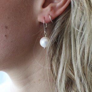 May include: A pair of silver dangle earrings with a large white pearl on each earring.