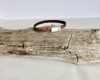 May include: A brown leather braided bracelet with a silver magnetic clasp.