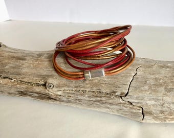 Pulsera de cuero tipo brazalete, elaborada con filas y filas de fino cuero italiano multicolor, y rematada con un cierre magnético de plata de calidad.