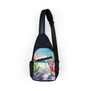 May include: Black sling bag with a colorful desert scene featuring cacti, mountains, and a cartoon character. The bag has a black adjustable strap and a small mesh pocket. The text "bocas del toro" is printed on the strap.