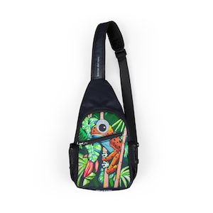May include: A navy blue sling bag featuring a colorful illustration of a frog in a jungle setting. The frog is orange and brown with a large eye. The bag has a black strap and a mesh side pocket. The text "bocas del toro" is printed on the strap.