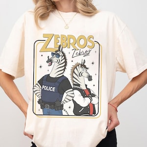 May include: A white ceramic mug with a black handle and the text "But First, Coffee" in a bold, black font. The mug is set against a blurred background, suggesting a cozy setting.