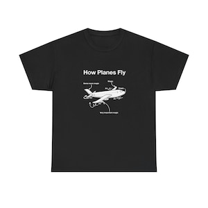 May include: Black t-shirt with a white graphic of an airplane and the text "How Planes Fly." The graphic includes labels such as "Magic" and "Very important magic," illustrating the concept of flight.