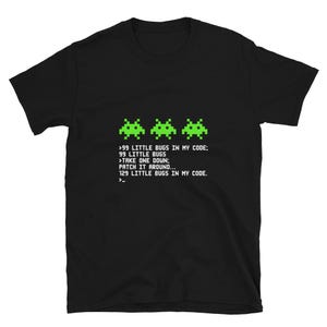 May include: Black t-shirt with a green pixelated image of three space invaders and text that reads: '>99 LITTLE BUGS IN MY CODE: 99 LITTLE BUGS >TAKE ONE DOWN: PATCH IT AROUND... 129 LITTLE BUGS IN MY CODE. >_'
