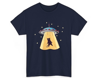May include: A navy blue short-sleeve t-shirt featuring a graphic of a gray UFO with red lights emitting a yellow tractor beam. A black cat is suspended within the beam, surrounded by small yellow stars against the dark fabric.