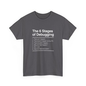 May include: A dark grey short-sleeve t-shirt featuring white text that reads: The 6 Stages of Debugging, 1. That can't happen. 2. That doesn't happen on my PC. 3. That shouldn't happen. 4. Why did that happen? 5. Oh, I see. 6. How did that ever work?