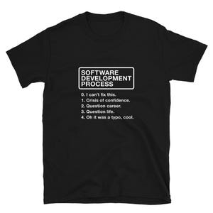 May include: Black t-shirt with white text that reads "SOFTWARE DEVELOPMENT PROCESS" and a list of steps: "0. I can't fix this. 1. Crisis of confidence. 2. Question career. 3. Question life. 4. Oh it was a typo, cool."