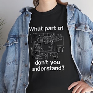 May include: Black t-shirt with white text and a circuit diagram. The text reads "What part of don't you understand?" The shirt is worn with a light blue denim jacket.