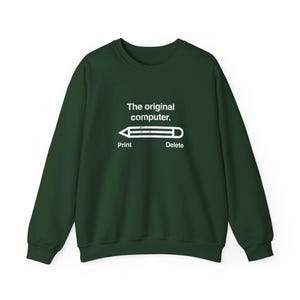 May include: A dark green crewneck sweatshirt featuring white text that reads The original computer. Below the text is a graphic of a pencil with the word Print on the left and the word Delete on the right side of the pencil illustration.