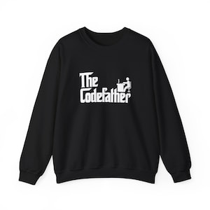 May include: A black long-sleeve sweatshirt featuring white text that reads The Codefather, accompanied by a small white graphic of a stick figure sitting at a desk with a computer, centred on the front of the garment.